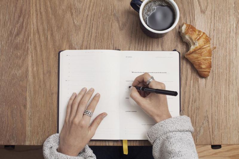 コーヒーを傍らにノートに書き込む手元