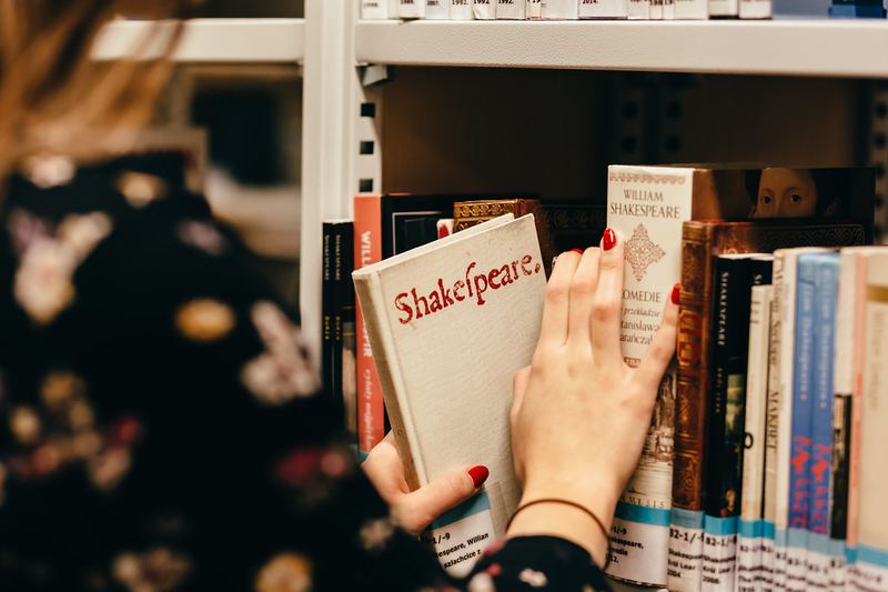図書館の書架から洋書を取り出す人