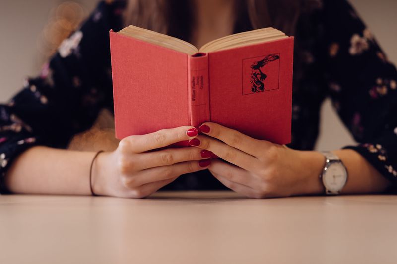 机に向かって赤い表紙の洋書を読む人